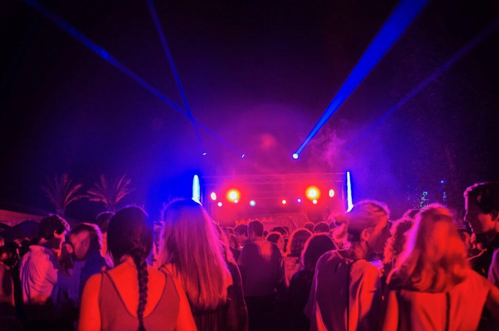 A crowd enjoying vibrant nightlife with colorful lights and music during a family vacation in Sotogrande, Spain.