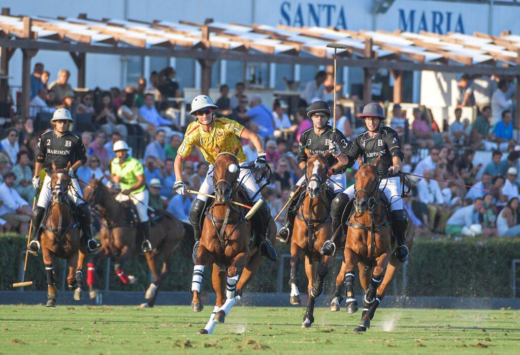 Players in action during a thrilling polo match in Sotogrande, Spain, with an audience watching from the stands.