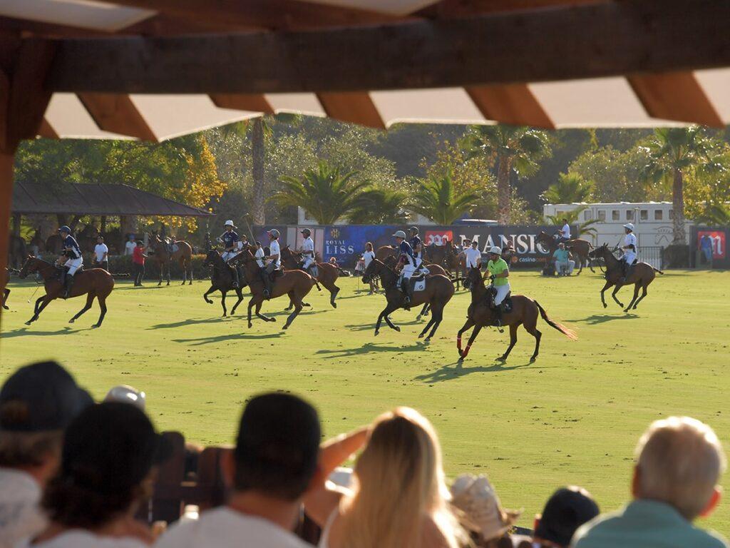 Spectators watching an exciting polo match at a Sotogrande property, with players on horseback in action on the field.