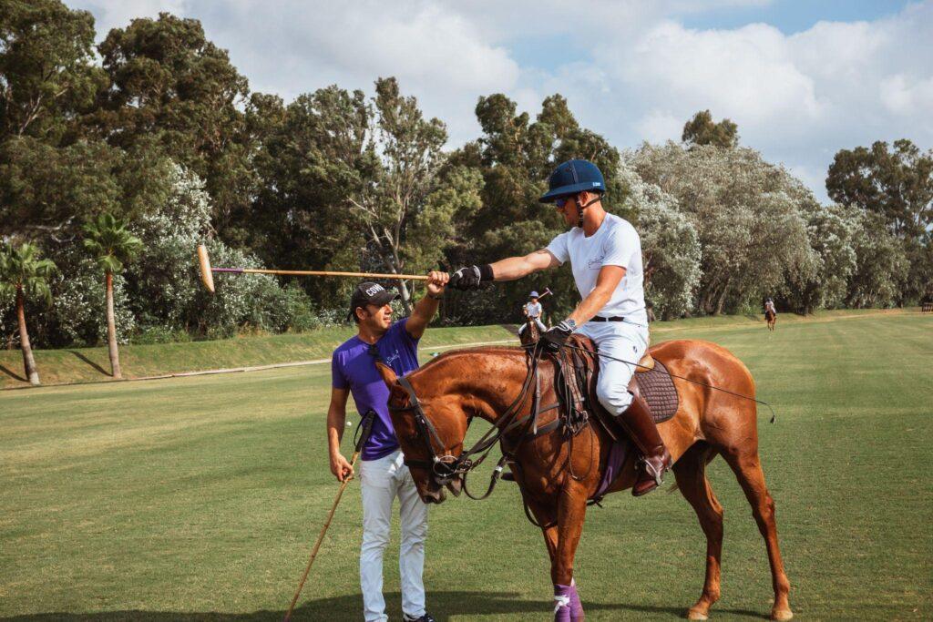 A polo player on horseback receives assistance from a teammate before a match in Sotogrande, Spain.