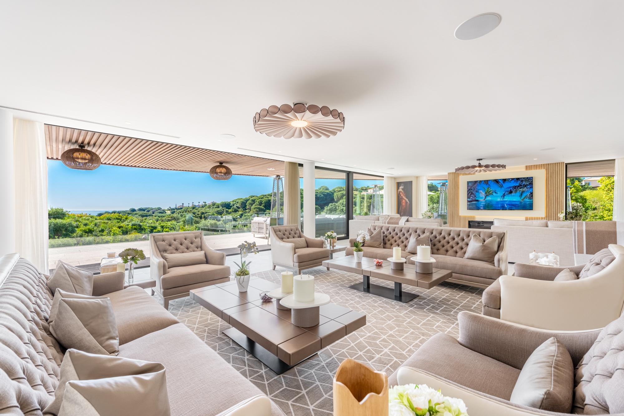 Modern bedroom in a luxury Sotogrande villa with floor-to-ceiling windows, a private terrace, and scenic views of the surrounding greenery.