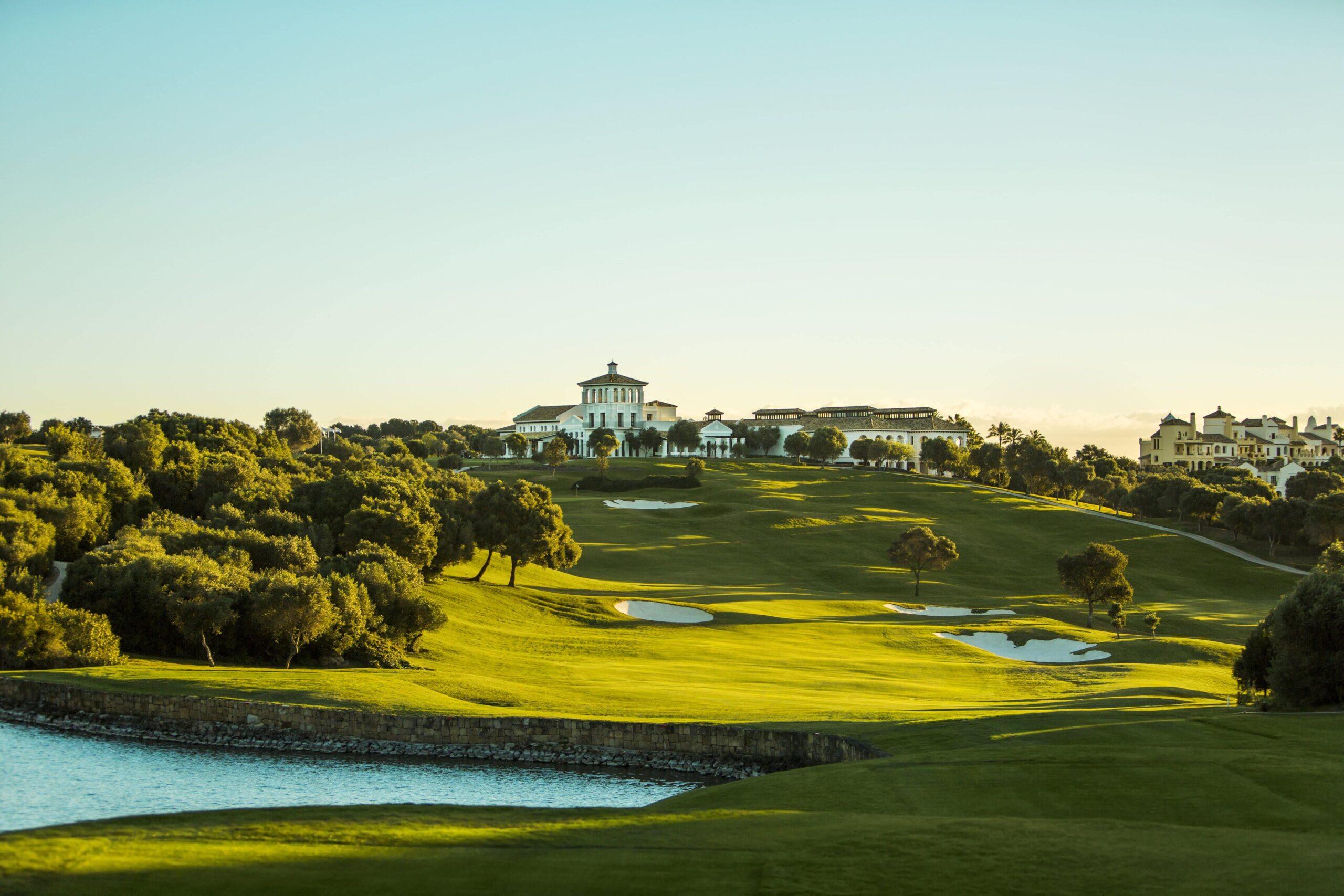 Scenic view of La Reserva Club's golf course with lush greenery and a grand clubhouse in the background.