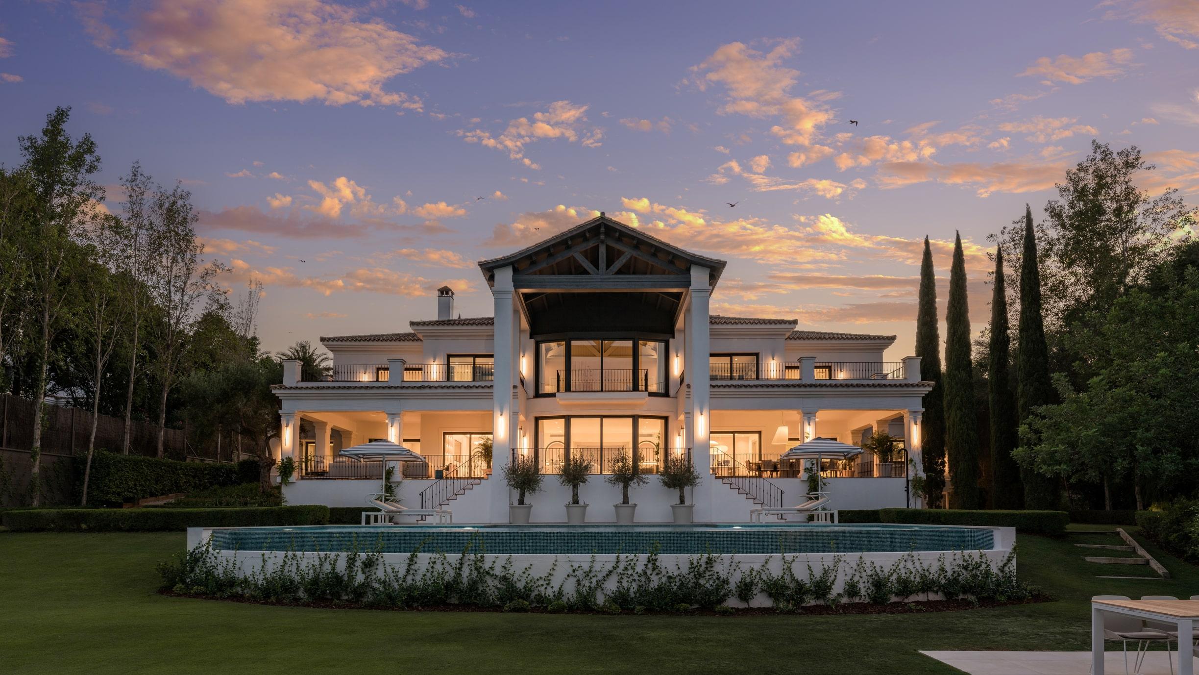 Grand luxury villa at sunset with illuminated terraces and landscaped gardens in Sotogrande.