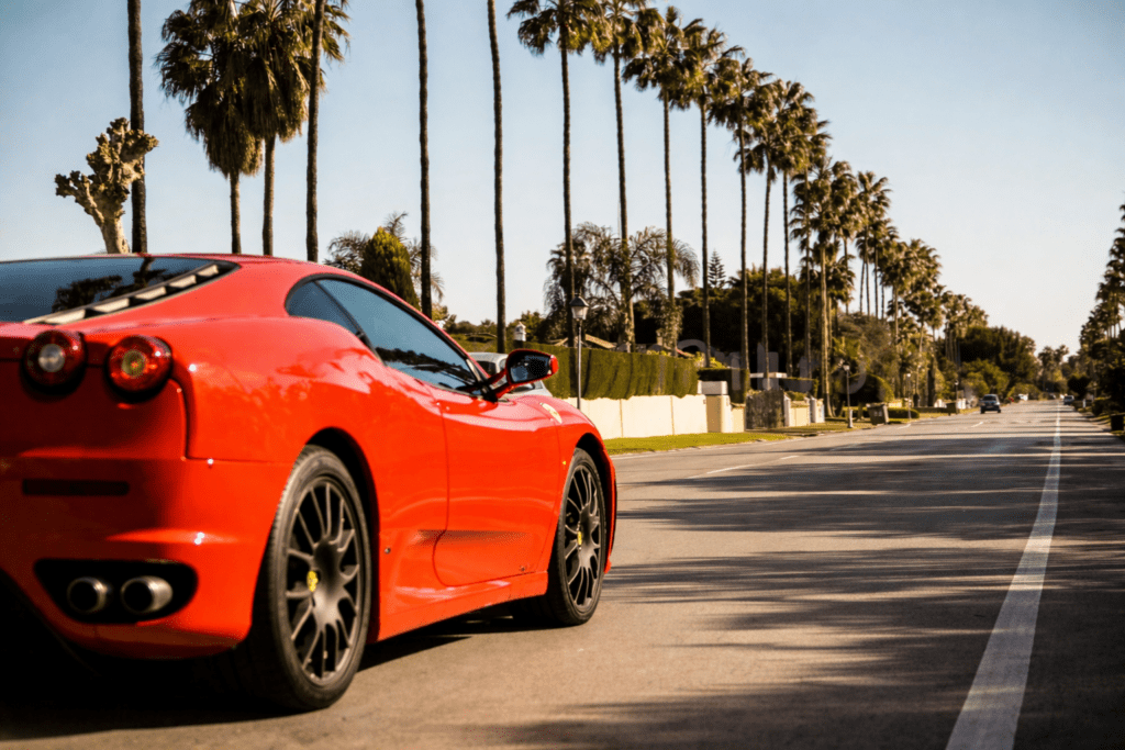 Ferrari driving through Paseo del Parque in Sotogrande surrounded by luxury villas and palm trees