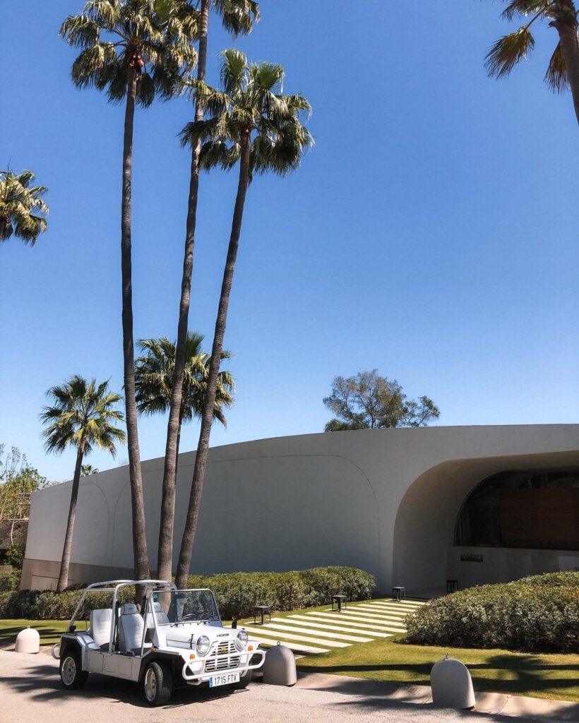 White electric Moke parked near a modern architectural villa under palm trees in Sotogrande