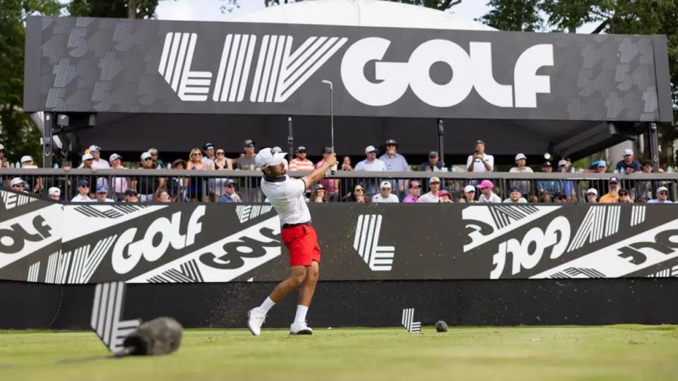 Golfer teeing off at a LIV Golf event in Sotogrande with a crowd and branded signage in the background
