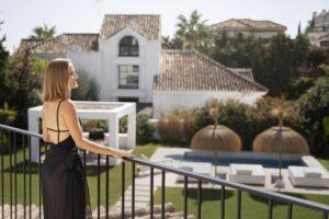 Woman enjoying the view from a balcony overlooking a luxury villa with pool in Sotogrande